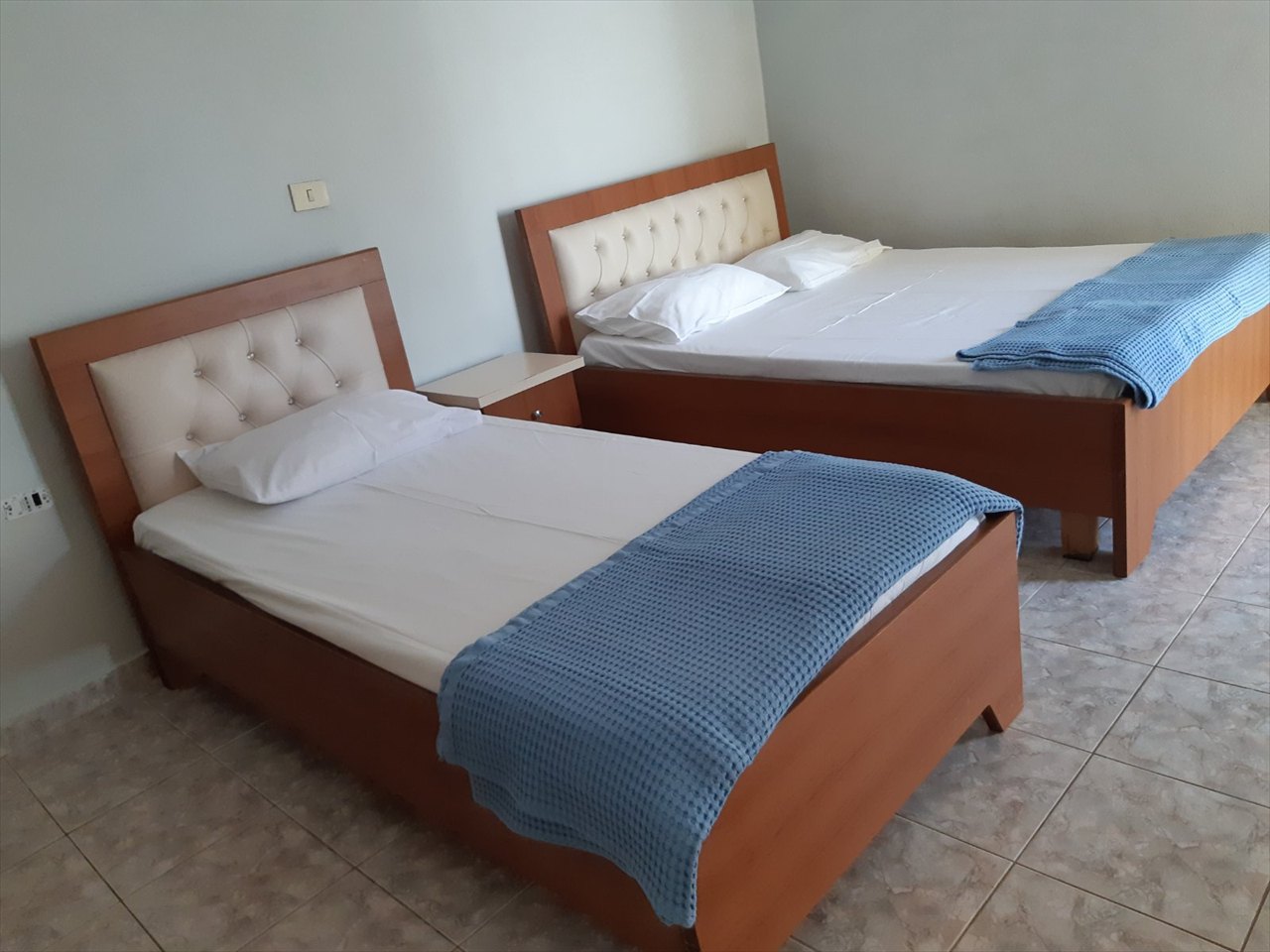 Guest room with one double bed and one single bed, dressed in white and blue bedding
